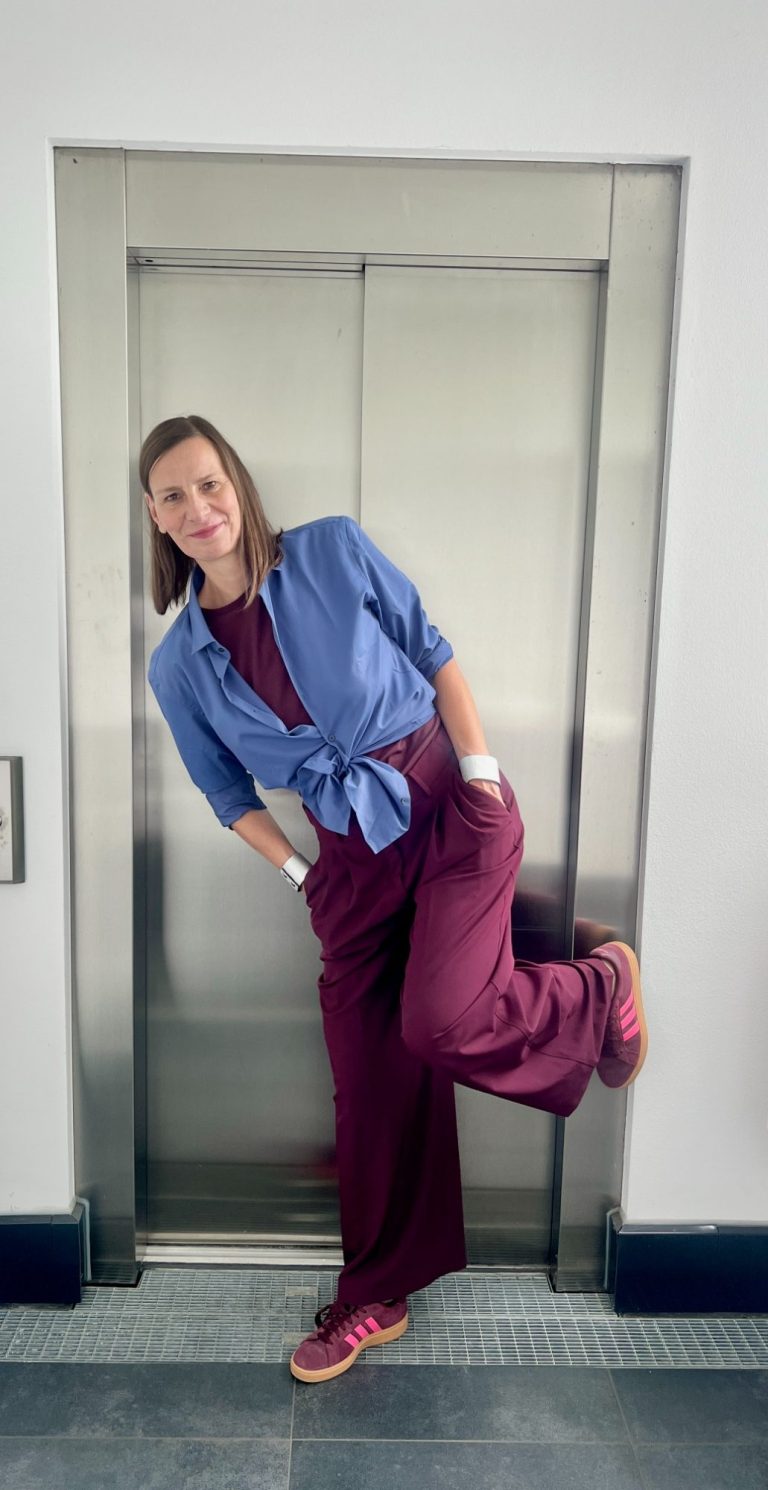 Gründerin vom Büro für Strahlkraft Ellen Schmitt mit lässiger Kleidung lehnt entspannt an einem Aufzug.
