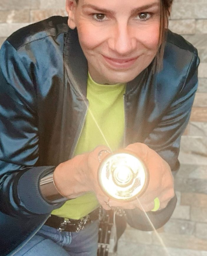 Strahlkraft erhöhen durch Stil Ellen Schmitt zeigt eine Taschenlampe, leuchtend, auf hellgrünem Hintergrund.