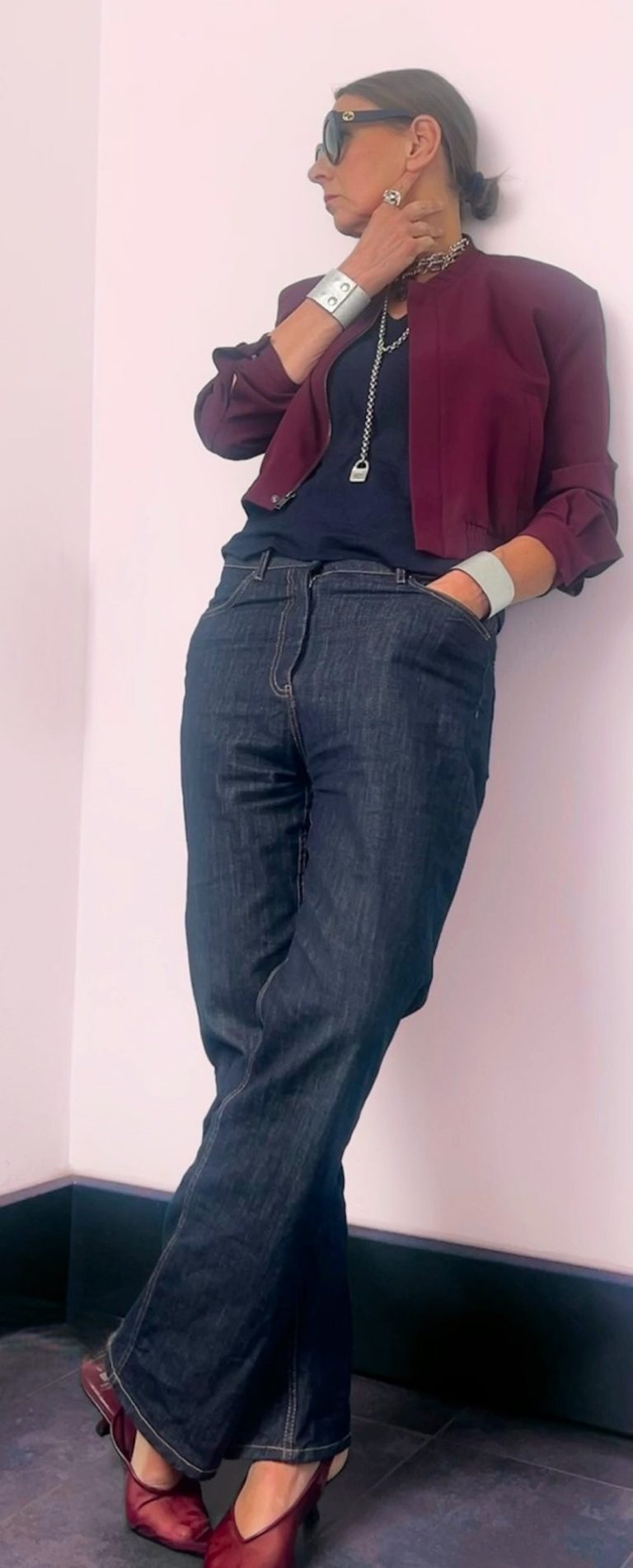 Farb- und Stilberatung Ellen Schmitt in modischer Kleidung, mit Sonnenbrille, steht entspannt an einer Wand.