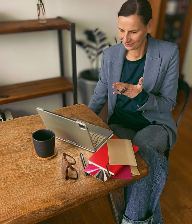 Individuelle Beratung Ellen Schmitt sitzt an einem Tisch, arbeitet an einem Laptop und hat Bücher sowie eine Tasse Kaffee.